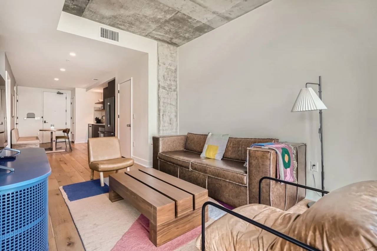 Bright living room in our downtown Austin condo with leather seating, a wood coffee table and an open dining area