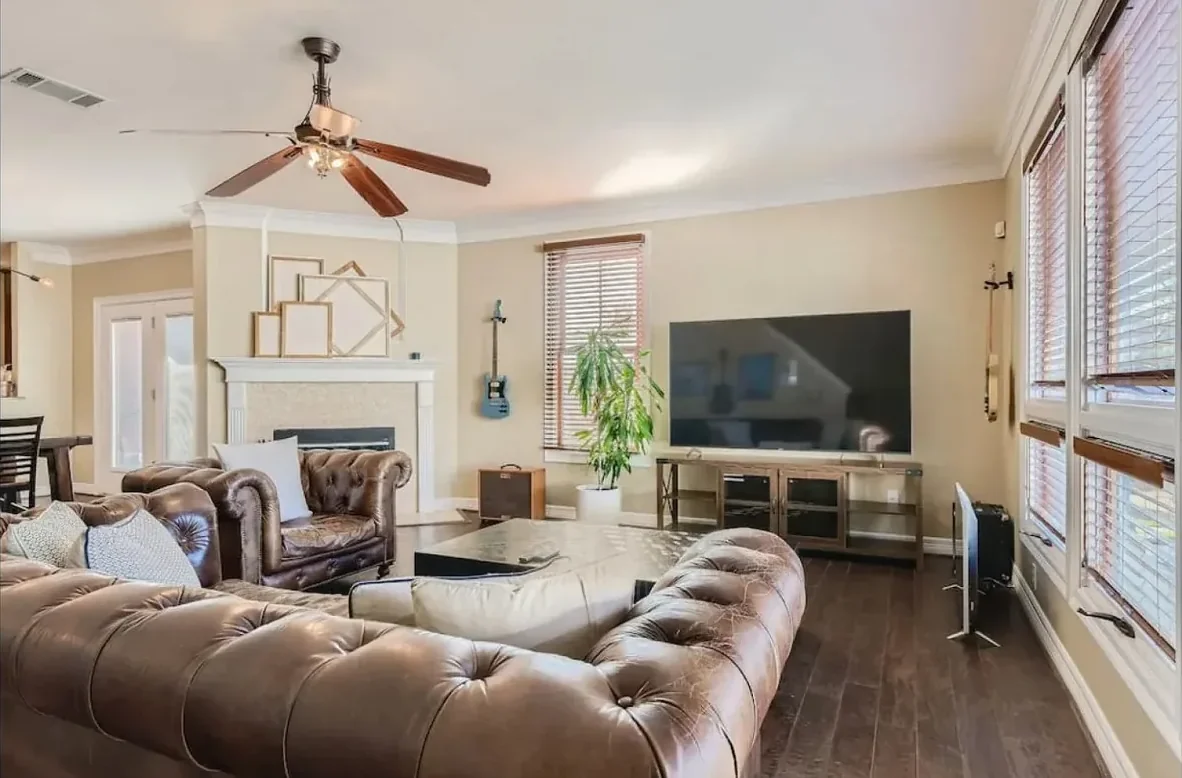 Austin living room with leather seating, a television, fireplace and large windows