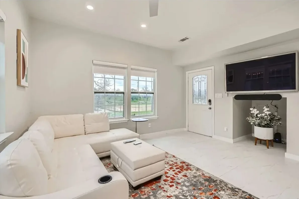 Austin living room with white seating, a patterned rug, ceiling fan, television and front door