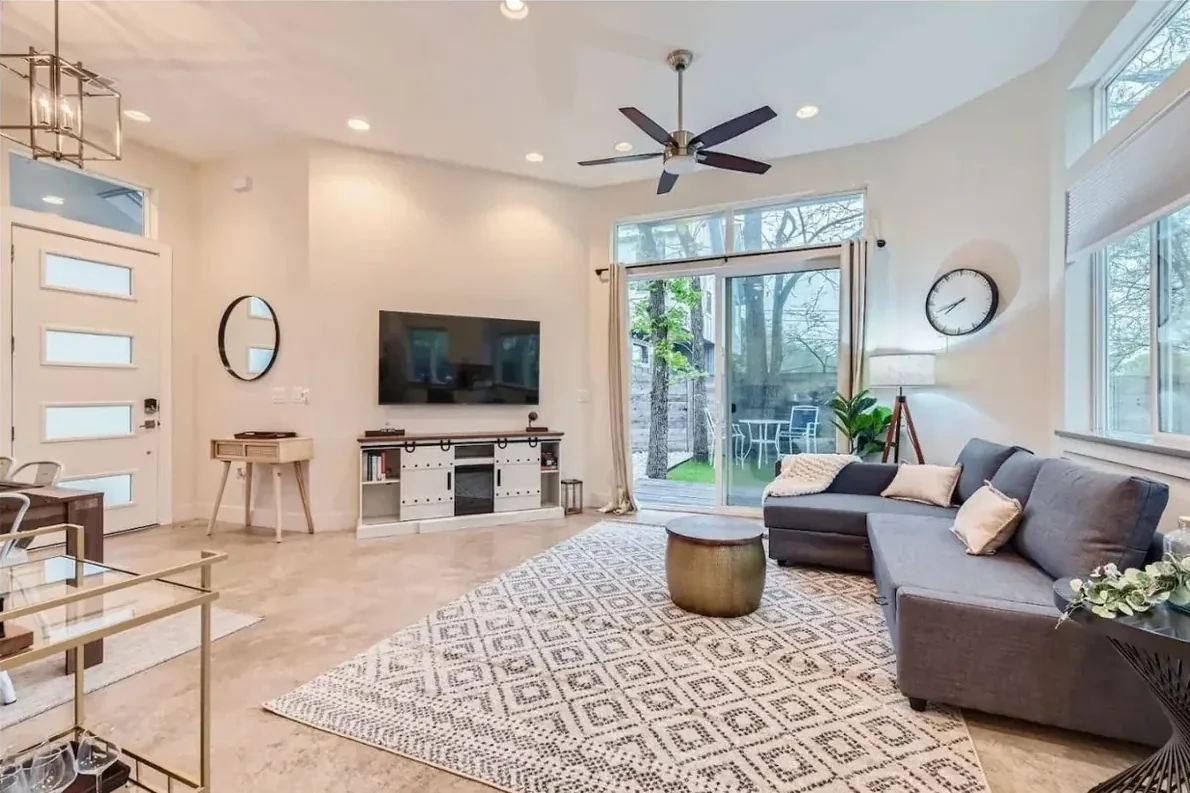 Austin living room with a gray sectional, wall-mounted television, sliding patio doors and large windows